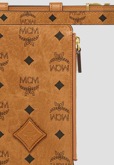 Bruine leren portfolio met een geperst zwart MCM-logo en diamanten patronen, met een goudkleurige rits en een gestructureerd oppervlak.