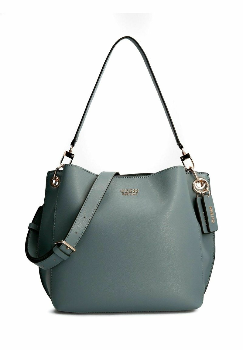 Sac à main en cuir bleu clair avec une quincaillerie dorée, une bandoulière et une étiquette logo "Guess" attachée sur le côté droit.