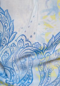 Light fabric with a blue and yellow paisley pattern, featuring intricate swirls and dots on a soft, textured background.