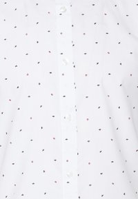 Camicia bianca con piccoli motivi a pois multicolori. Chiusura con bottoni sul davanti e bottoni rotondi. Texture liscia, design del colletto standard.