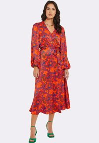 Langes Wickelkleid in leuchtendem Rot mit floralem und abstraktem Muster in Blau und Grün. Verfügt über Puffärmel und eine geschnürte Taille.