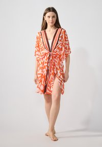 Kimono leggero e trasparente di un brillante arancione con motivi astratti bianchi. Presenta un profondo scollo a V e una vita con nastro per una vestibilità regolabile.