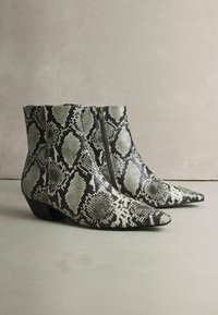 Fekete-fehér kígyóbőr mintázatú bokacsizma, hegyes orral és oldalsó zipzárral. Alacsony blokk sarkú. Sima felület.