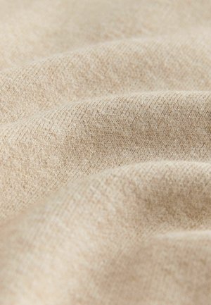 Beez värvusega tekstuuriga kangas, millel on pehme, kudumise välimus, kuvades peeneid värvi ja mustri variatsioone, rõhutades selle käega katsumise kvaliteeti.