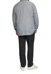 Lichtblauw, textuurgebufferd overhemd met een ronde zoom, gecombineerd met zwarte, tapered broek en witte sneakers. Zichtbare naden en manchetten.