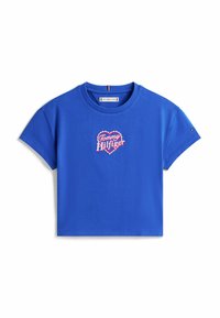 Camiseta de algodón azul con mangas cortas, que presenta un logo de corazón bordado en rojo y blanco, con una etiqueta que muestra el nombre de la marca en el cuello.