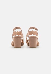 Sandales à talons ouverts et nus avec une tige texturée, un design festonné sur les brides et un talon épais. Equipées d'une sangle de cheville réglable.