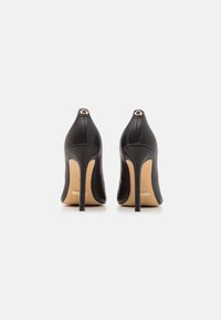 Black leather high-heeled shoes with a pointed toe and a sleek silhouette. Features a gold-toned accent at the heel and a smooth texture.