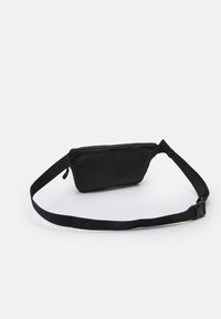 Musta kangas vyölaukku, jossa on suorakulmainen muoto, vetoketjusuljenta ja säädettävä hihna. Sileä rakenne, minimalistinen muotoilu ja ei näkyviä kuvioita.