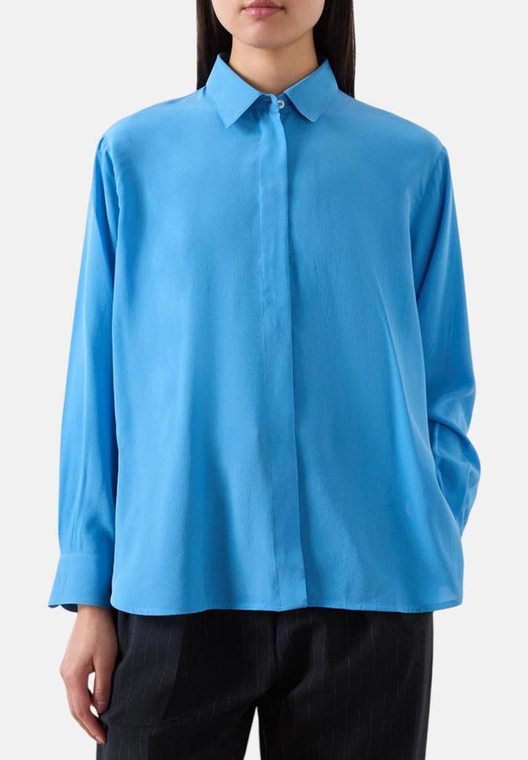 Camicia a maniche lunghe blu chiaro con colletto a punta, realizzata in tessuto liscio. Presenta una chiusura con bottoni e una vestibilità comoda.