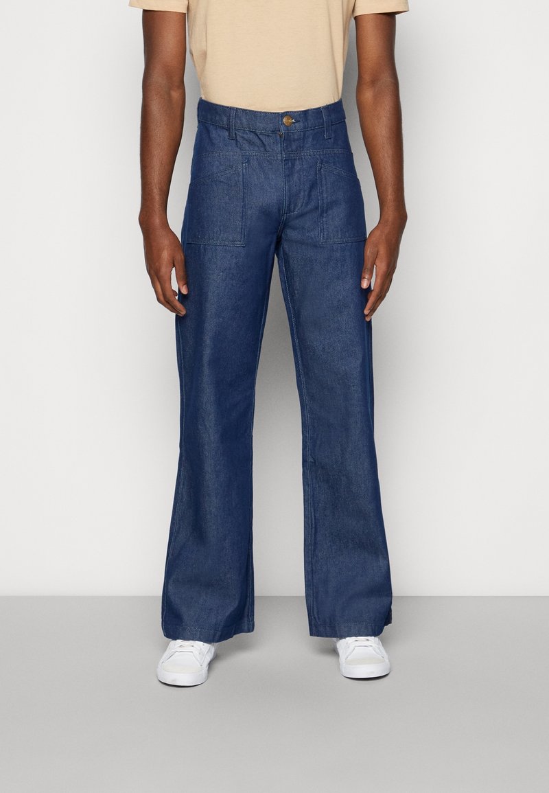 Blå denimbyxor med avslappnad passform, raka ben och stora framfickor. Avslutade med knappstängning och sömlös fåll.