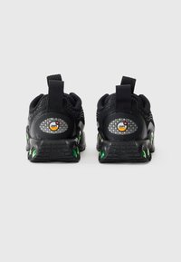 Ζευγάρι μαύρων Nike Air Max αθλητικών παπουτσιών που εμφανίζεται από το πίσω μέρος, με πράσινες λεπτομέρειες αεροστιβαρότητας και θηλιές, σε λευκό φόντο.