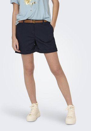 Un short bleu marine avec un ourlet retroussé et une ceinture tissée marron, assorti à des baskets montantes blanches. Le tissu semble léger et décontracté.