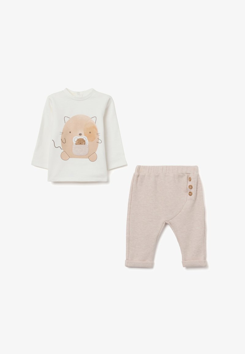 Top de manga larga de color claro con un gráfico de animal de dibujos animados, combinado con pantalones beige de textura suave que tienen tres acentos de botones.