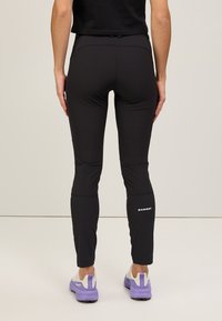 Svarta fukttransporterande tights med en åtsittande design, med knäpaneler och en vit "Mammut"-logotyp vid underbenet.