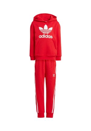 Chándal de algodón rojo que incluye una sudadera con capucha con un logotipo blanco y pantalones a juego con franjas blancas en los laterales. Textura suave y corte relajado.