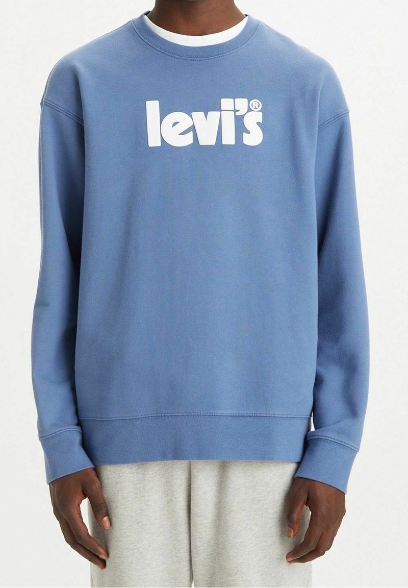 Sininen pyöreä pääntiehuppari, joka on valmistettu puuvillasta. Edessä on suuri valkoinen "levi's" -logo. Rentoa muotoilua, jossa ribbireunat hihansuissa ja helmassa.