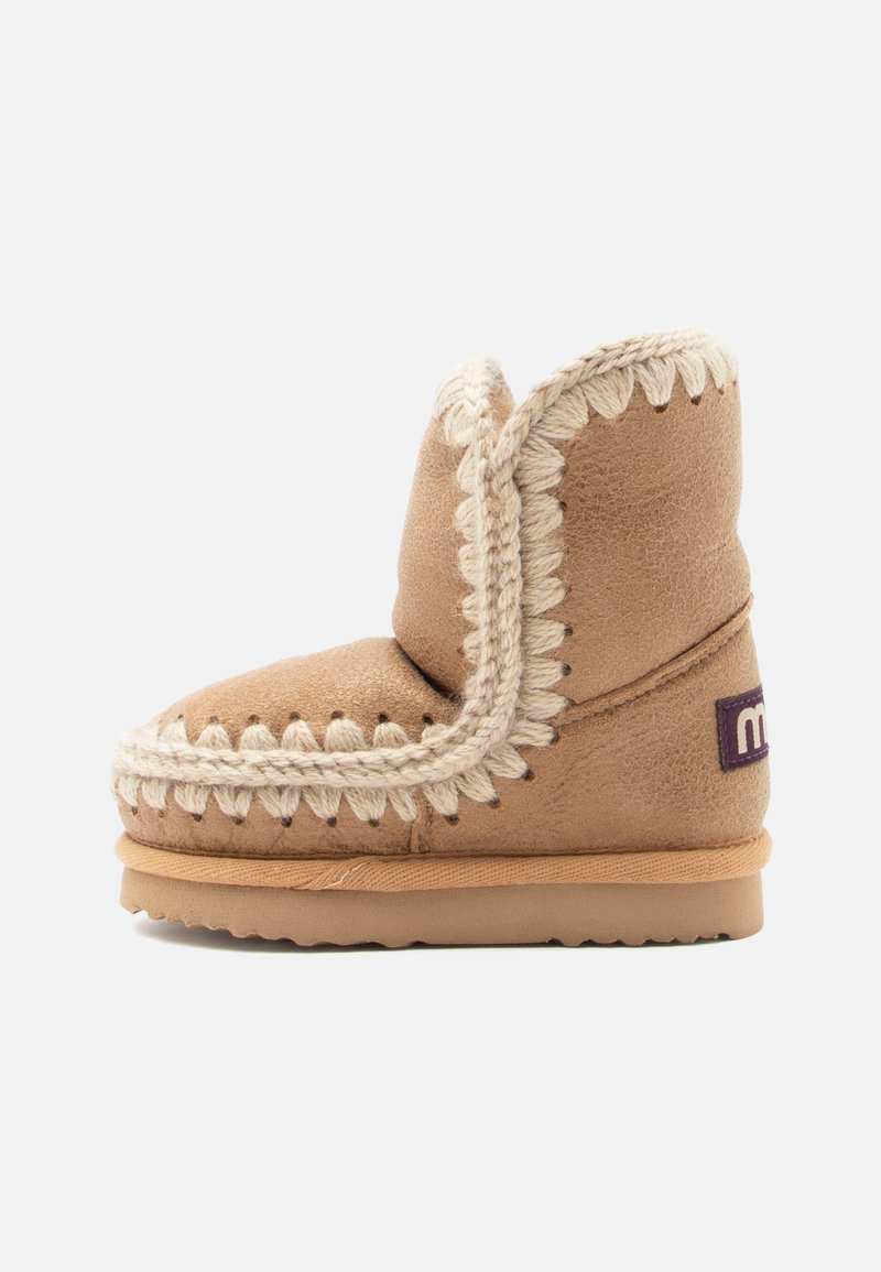 Χακί σουέτ μποτάκι με μπεζ πλεγμένη λεπτομέρεια γύρω από την άκρη και ευέλικτη σόλα. Διαθέτει ένα μικρό μωβ λογότυπο στο πλάι.