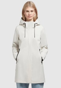 Impermeabile leggero color crema con cappuccio, materiale impermeabile, cordini regolabili e tasche con zip nere.