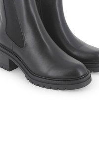 Las botas de tobillo de cuero negro presentan una punta cuadrada, paneles laterales elásticos dobles y una suela de goma gruesa con taquetes para mayor tracción.