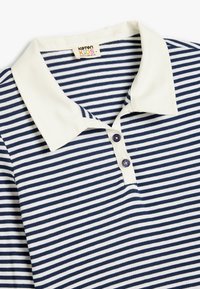 Navy ja valged triibudega polo särk, millel on kreemivärvi krae ja kaks lilla nuppu placket'il, valmistatud puuvillast.