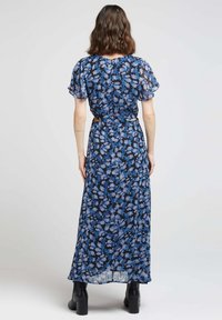 Robe maxi florale avec des manches courtes à volants, fond bleu foncé et motif floral bleu clair. Comprend une taille ceinturée et un tissu fluide.