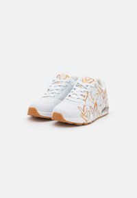 Sneakers bianchi con motivi astratti arancioni, dotati di una parte superiore testurizzata, pannelli in rete e una suola in gomma con grip a nido d'ape.