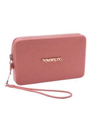 Clutch da polso rettangolare rosa con superficie strutturata, chiusura con zip e logo "havaianas" in lettere metalliche sul davanti.