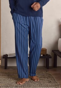 Vīriešu tumši zili pidžamu bikses ar vertikālām baltām svītrām. Viegls audums, brīva piegriezuma, elastīga josta un smalka tekstūra.