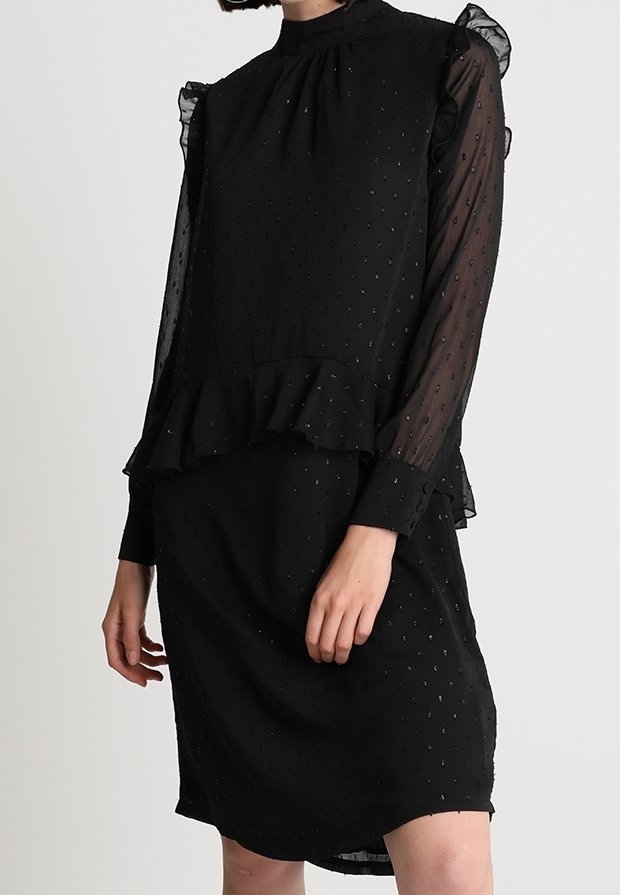Musta mekko, jossa on röyhelökaulus ja -hihat, valmistettu teksturoidusta kankaasta, jossa on hienovaraisia kuvioita, ja siinä on kerroksellinen peplum-muotoilu.