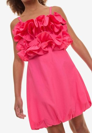Fuchsia kjole med flæseoverlay, tynde skulderstropper og en rynket kant. Fremstillet af letvægtsstof med glat tekstur og dristig farve.