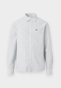 Striped button-up shirt in light blue and white. Cotton fabric, long sleeves, pointed collar, featuring a small green logo on the chest pocket.