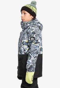 Veste de ski colorée avec des motifs abstraits en bleu, noir et vert. Comprend une capuche, des poignets réglables et des gants jaunes fluo.