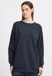 Marineblå sweatshirt med afslappet pasform, rund halsudskæring og ribbede manchetter. Blød tekstur, enkelt design og ingen dekorationer.