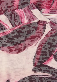 Kortärmad tygtopp med ett rosa och grått abstrakt mönster, mjuk textur och subtila färgvariationer.