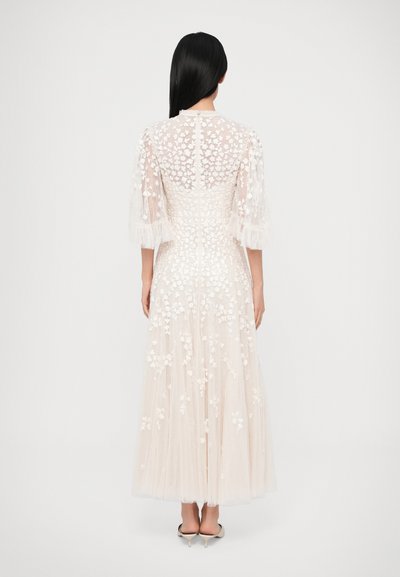 Dlhé krémové šaty s kvetinovou výšivkou. Priehľadná vrstva, nafúknuté rukávy a viacvrstvová sukňa. Zadná časť so zapínaním na gombíky.