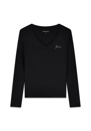 Chemise noire à manches longues et col en V avec petit logo "Guess" en strass sur le côté gauche de la poitrine, présentée à plat sur fond blanc.