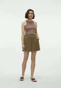 Brown sleeveless top paired with olive green high-waisted shorts featuring front pockets and button accents. Worn with black slide sandals.