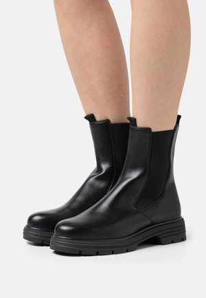 Bottines en cuir noir avec des panneaux élastiques sur les côtés, bout arrondi, semelle texturée et languettes pour un enfilage facile.