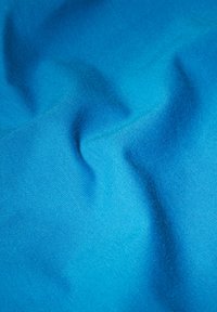 Ljust blått tyg med en slät yta, som har lätt veck och en subtil lyster. Materialet visar fin ribbning genom hela ytan.