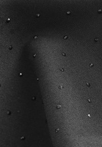 Black fabric featuring a textured surface with small, shiny black sequins scattered throughout, creating a subtle, dotted pattern.