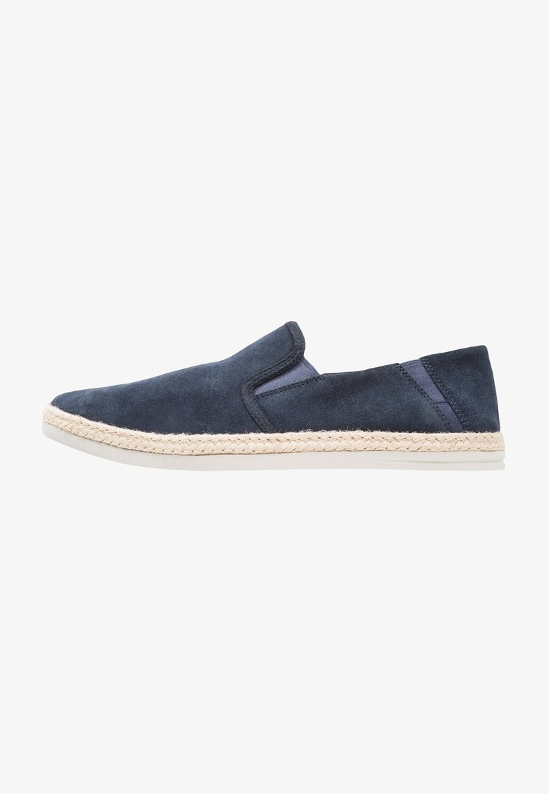 Chaussures slip-on en suede marine avec une semelle en jute de style espadrille. Présente des panneaux latéraux élastiques et une finition lisse semblable à du cuir.