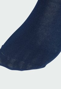 Námornícke modré ponožky vyrobené z textúrovanej látky, s elegantným dizajnom a hladkým okrajom. Detailný pohľad zdôrazňuje šitie.