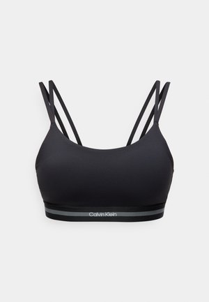 Melnā sporta krūšturis ar divām plānām plecu siksnām un elastīgu joslu, kurā baltā krāsā ir uzraksts “Calvin Klein” ar pelēkām svītrām.