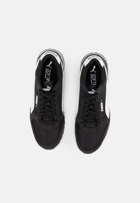Black athletic sneakers with a fabric upper, white accents, and textured soles. Features flat laces and cushioned insoles.