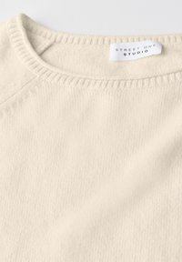 Maglione a maglia color crema con scollo rotondo e un'etichetta bianca che recita "STREET ONE STUDIO" all'interno del colletto.