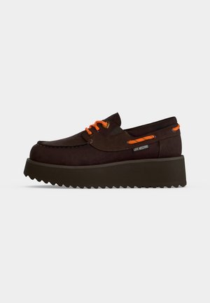 Mocassin à plateforme marron foncé avec lacets et bordures orange vif, semelle côtelée et étiquette Love Moschino sur le côté.