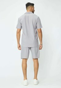 Chemise grise à manches courtes et shorts assortis en tissu texturé. Comprend un col, une coupe décontractée et des shorts arrivant au genou.