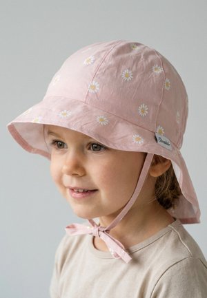 Young child wearing a pink sun hat with white daisy patterns and chin straps, smiling and looking slightly to the side.