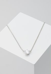 Silver kedja med ett centralt runt slipskärningsstål i en kantsatt fattning. Kedjan har en ömtålig länkdesign.